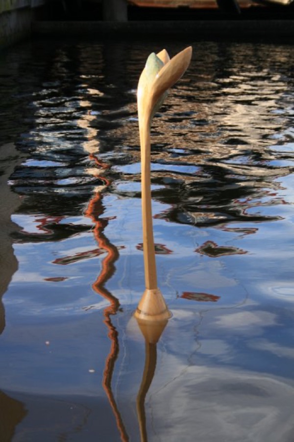 Houten bloemvormig kunstwerk dat uit het water van de gracht steekt