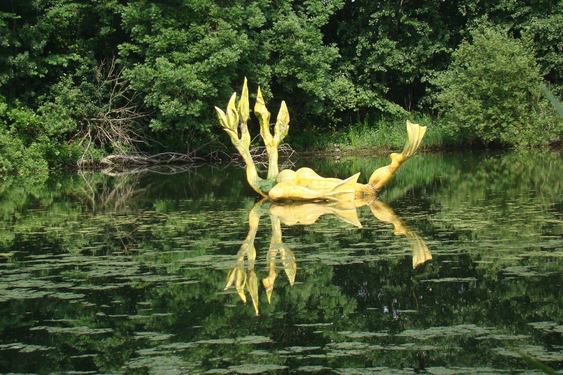 Geel kunstwerk dat in de gracht drijft, met spiegeling in het water
