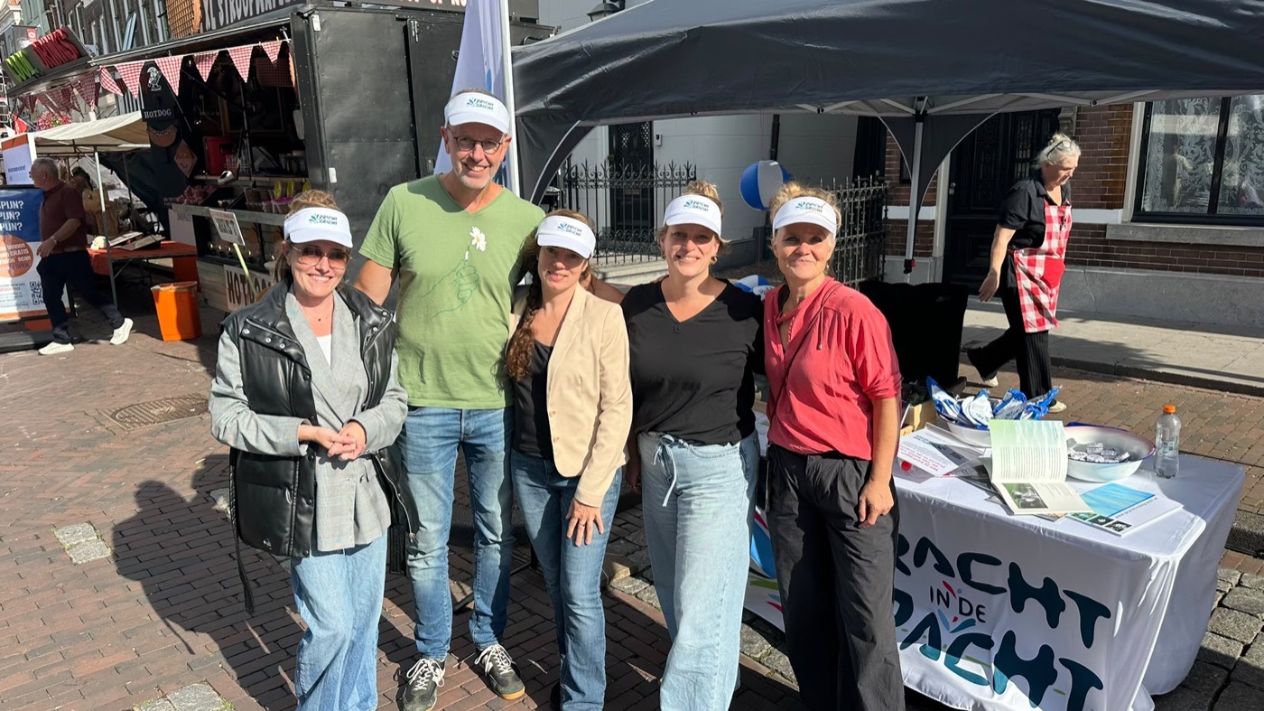 Het team van Pracht in de Gracht met kunstenaar Leontien Vossen achter de kraam op de braderie in Zaltbommel